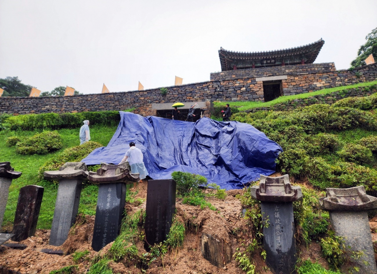 Gongju city officials place a tarpaulin in front of the Geumseoru gate at Gongsanseong in Gongju, South Chungcheong Province, on Saturday to prevent further damage. (Gongju City)
