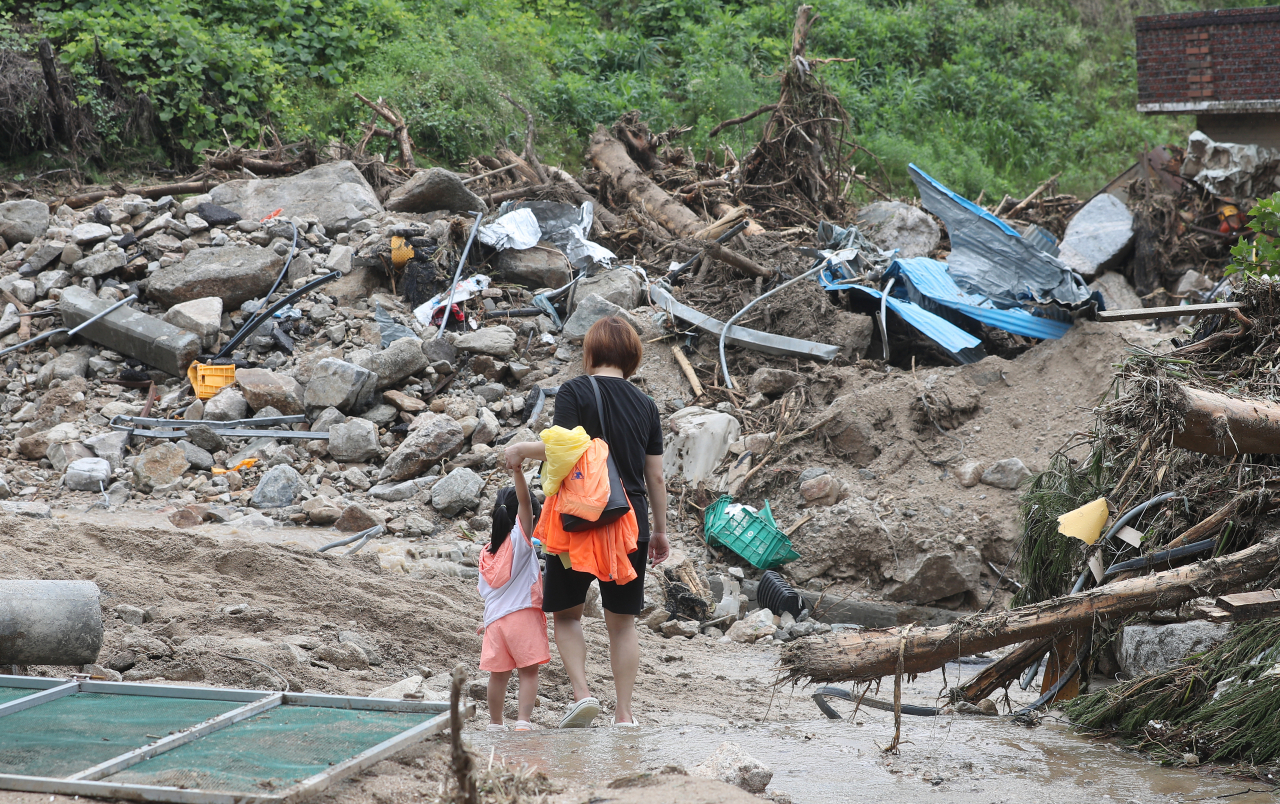 Residents of Beolbang-ri in Yecheon, North Gyeongsang Province, walk through the landslide-stricken village on Sunday. (Yonhap)