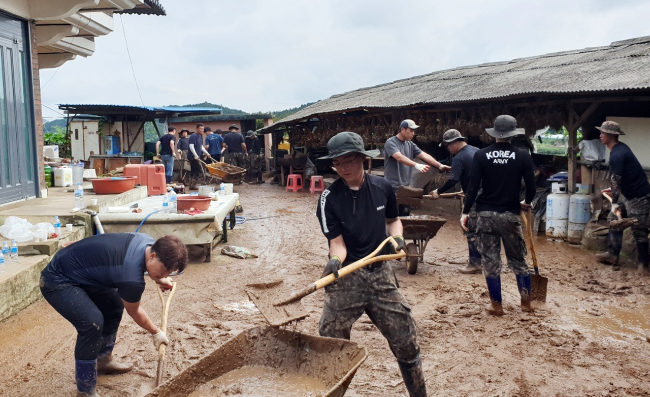Army soldiers remove mud left after monsoon rains that had been pouring since Saturday at a house in Cheongyang-gun, South Chungcheong Province, Monday. (Yonhap)