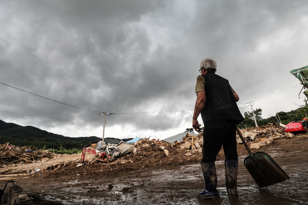 A resident is seen assessing damaged property under approaching rain clouds in the village of Jinpyeong-2-ri, Gamcheon-myeon, Yecheon-gun, North Gyeongsang Province, which was devastated by a landslide triggered by torrential rains on Monday. Yecheon-gun issued safety warnings to residents of areas experiencing heavy downpours once again on the day. (Yonhap)