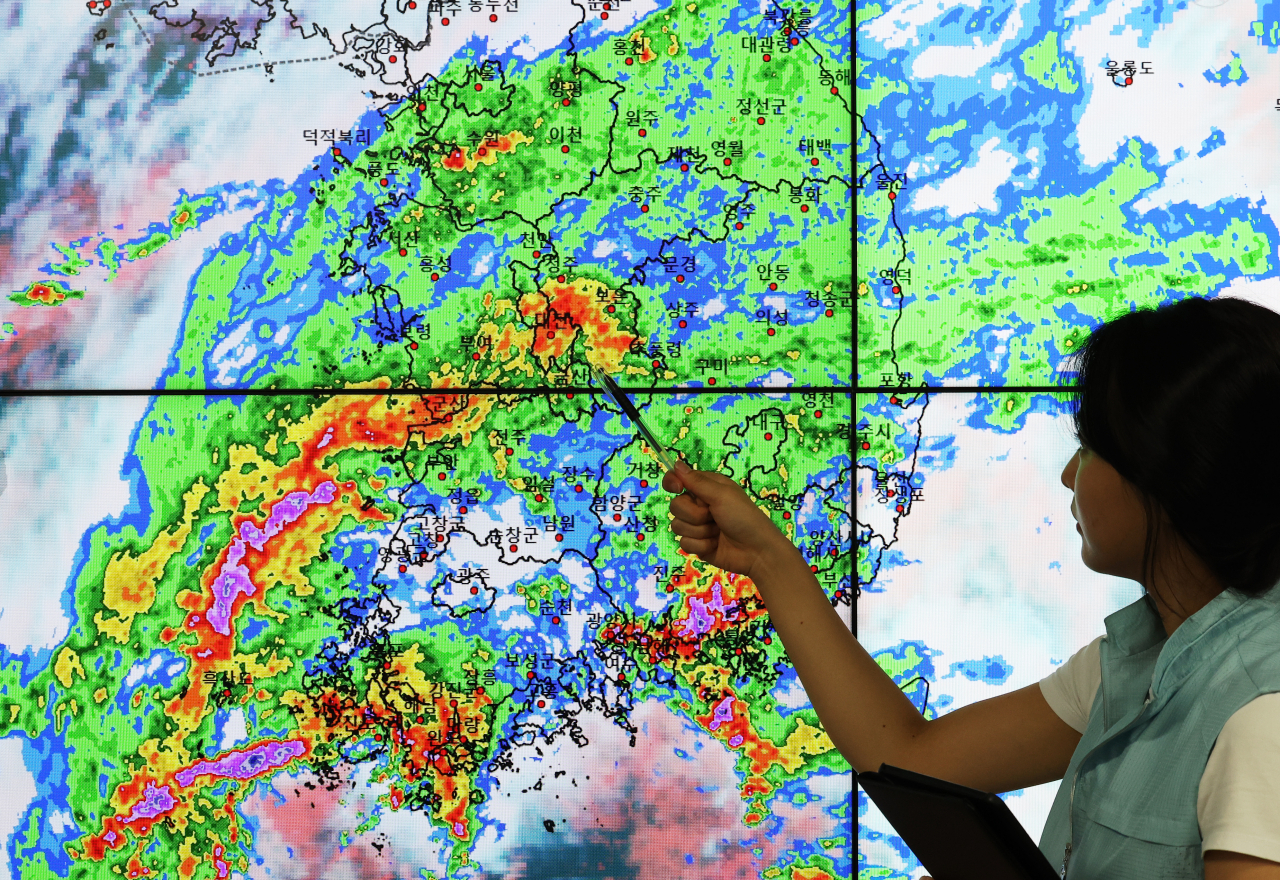 A Korea Meteorological Administration official points at infrared satellite imagery of South Korea affected by heavy monsoon rains as of Tuesday morning. (Yonhap)