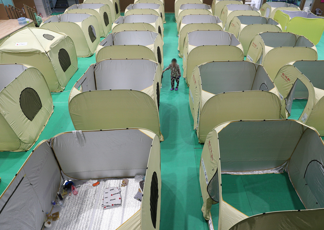 A flood victim walks between tents used as temporary shelter inside a community sports center in Yecheon, North Gyeongsang Province, Friday. (Yonhap)