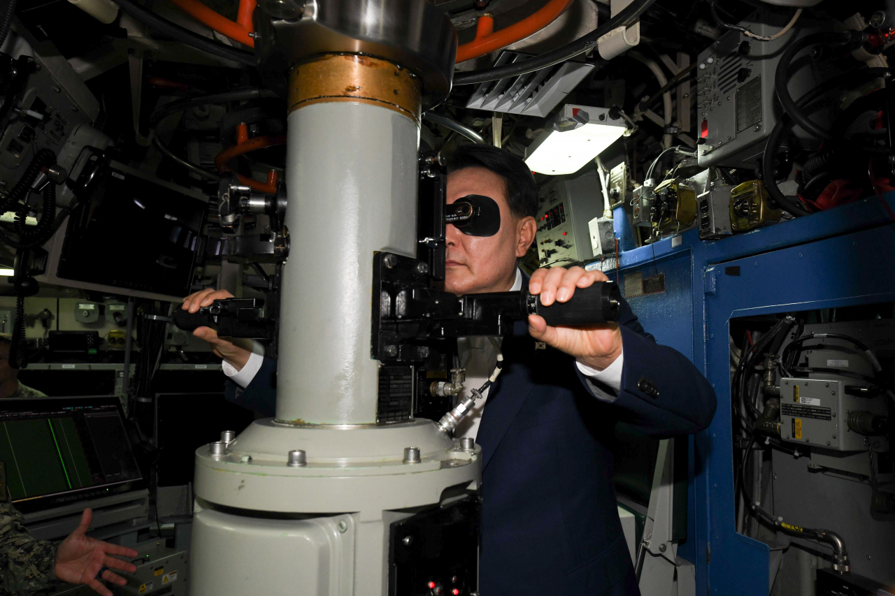 President Yoon Suk Yeol looks through the periscope while inspecting the inside of the USS Kentucky, an Ohio-class nuclear-powered ballistic missile submarine that arrived at Busan on Wednesday. (Yonhap)