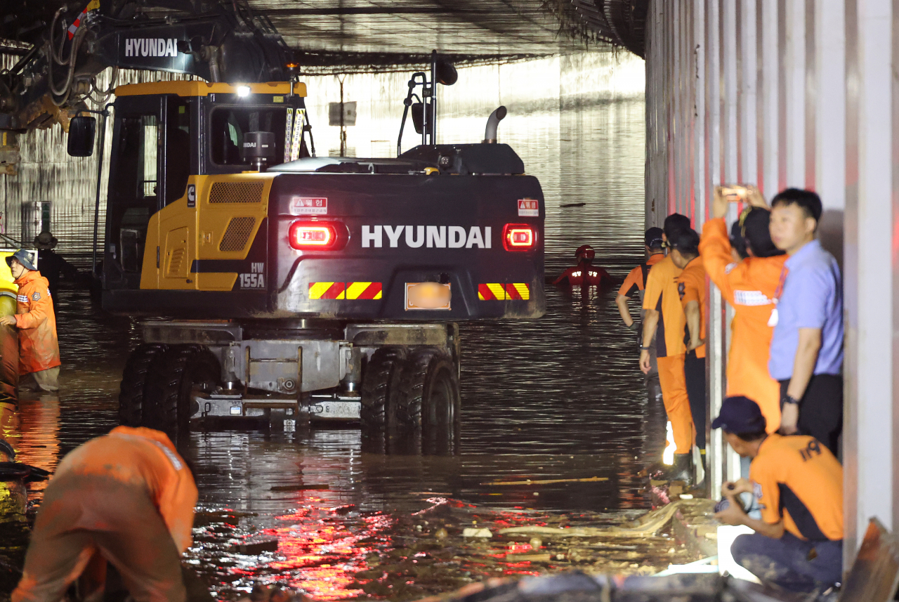 Rescuers on Monday, including the Coast Guard, search on foot in the Gunpyeong underpass in Osong, Cheongju, North Chungcheong Province, which was flooded due to torrential rain on July 17. (Yonhap)
