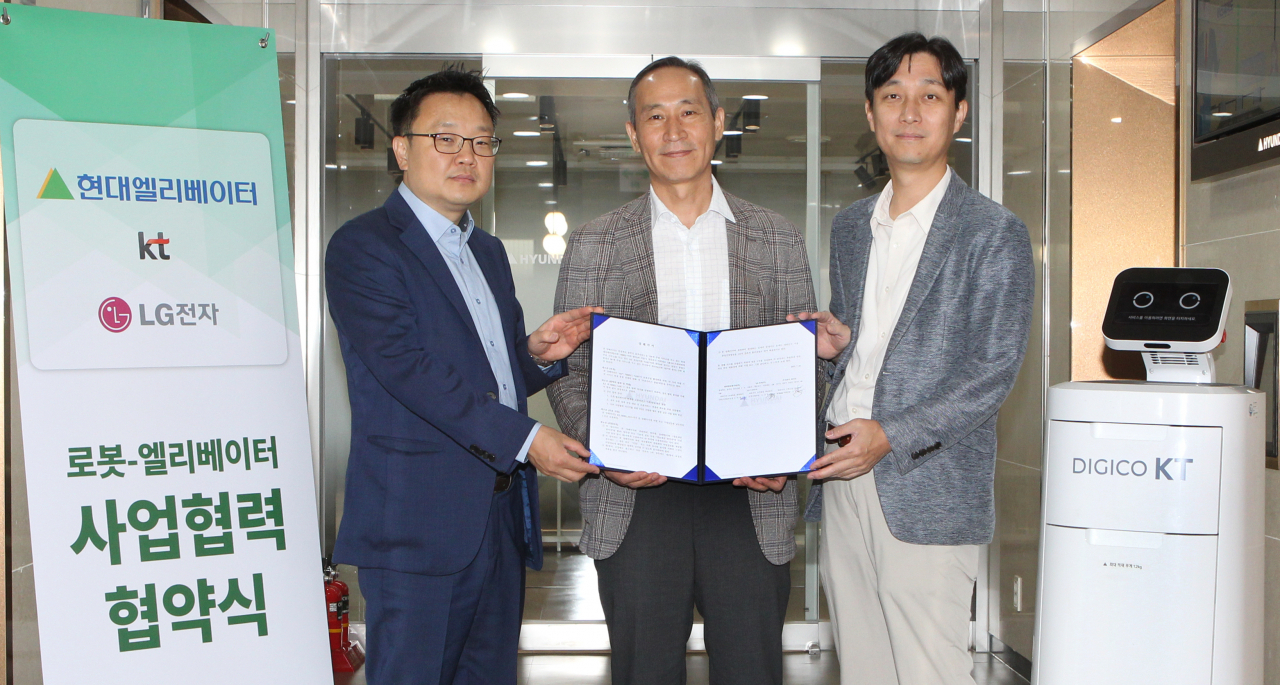 From left: Lee Sang-ho, head of the AI Robot Business Unit at KT; Do Ik-han, head of the Service Business Division at Hyundai Elevator; and Roh Kyu-chan, leader of the Robot Business Division at LG Electronics, pose for a photo after signing a memorandum of understanding for a robot-elevator partnership in Seoul on Wednesday. (Hyundai Elevator)