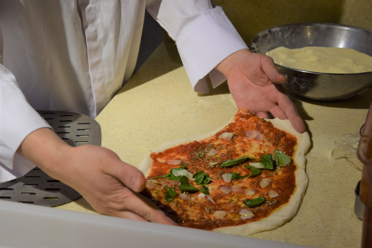 Yu spreads out the dough to ensure the pizza is evenly shaped. (Kim Hae-yeon/ The Korea Herald)