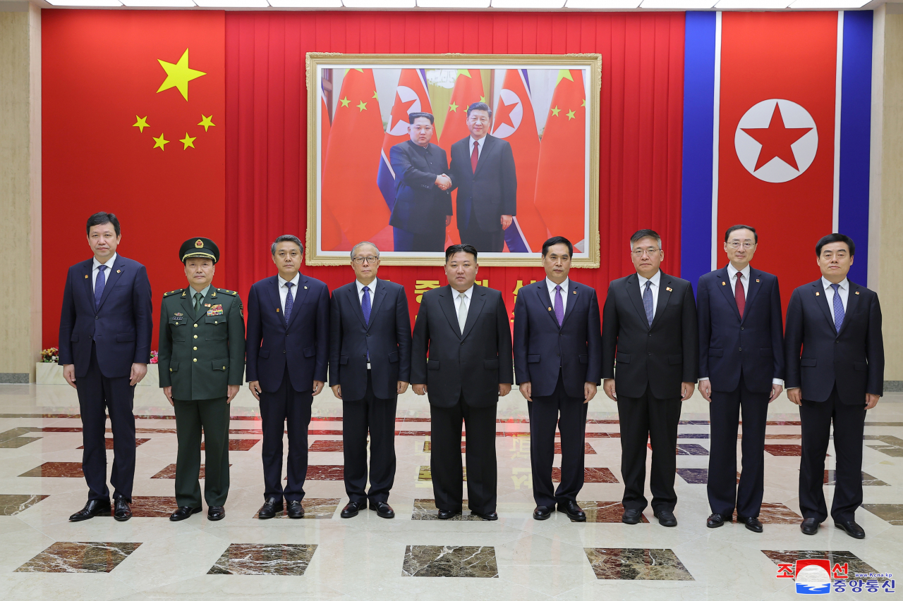 North Korean leader Kim Jong-un (center) poses for a photo with North Korean officials and a Chinese delegation after their meeting on Friday. (North's Korean Central News Agency)