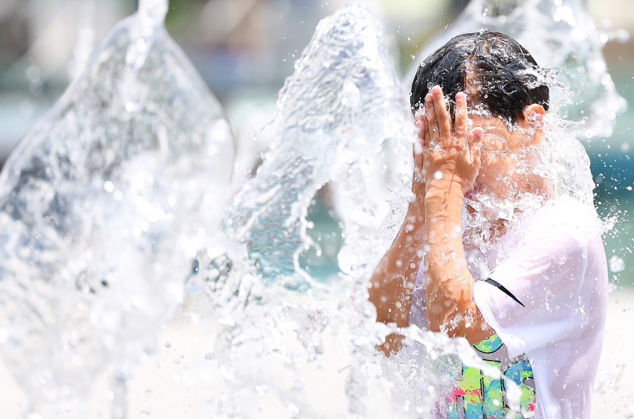 A child cooling down in a fountain at Gwanghwamun Square in downtown Seoul. (Yonhap)