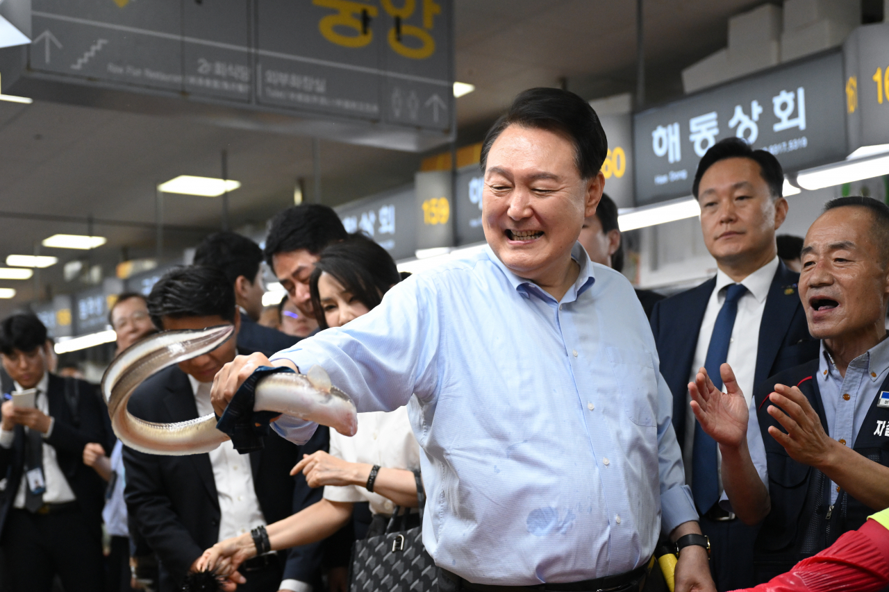 President Yoon Suk Yeol (third from right) holds an eel during his visit to Jagalchi Market in Busan on Thursday (Presidential Office)