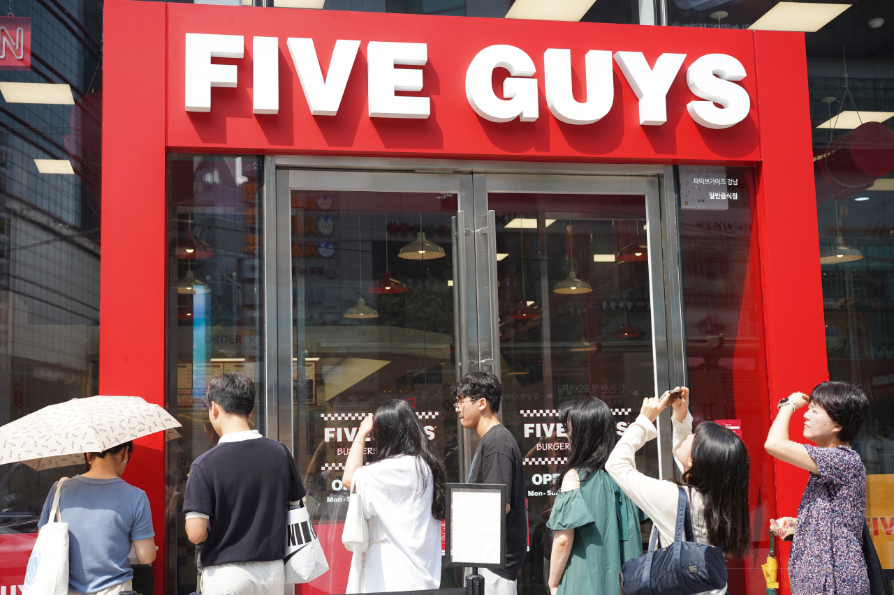 Visitors wait in line to enter their phone numbers on a tablet in front of the Five Guys burger restaurant located in Gangnam-gu, southern Seoul, on Tuesday.