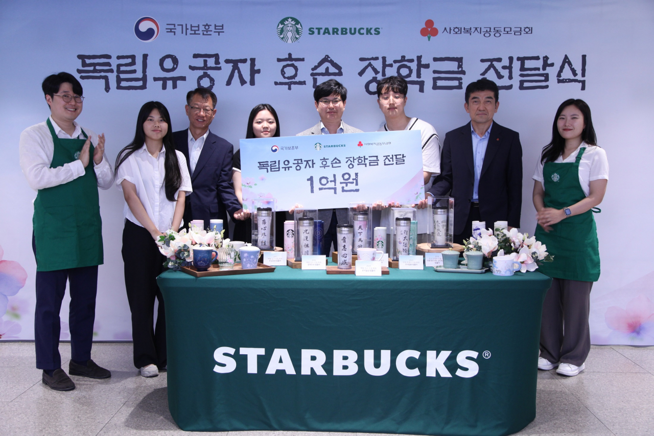 Seoul Veterans Affairs Regional Office Director Na Chi-man (third from left), and Starbucks Korea Chief Administrative Officer Kim Nak-ho (center, fifth from left), and student beneficiaries pose for a photo as part of the donation ceremony held at Starbucks Academy Center in Sogong-dong, Seoul, on Tuesday (Starbucks Korea)