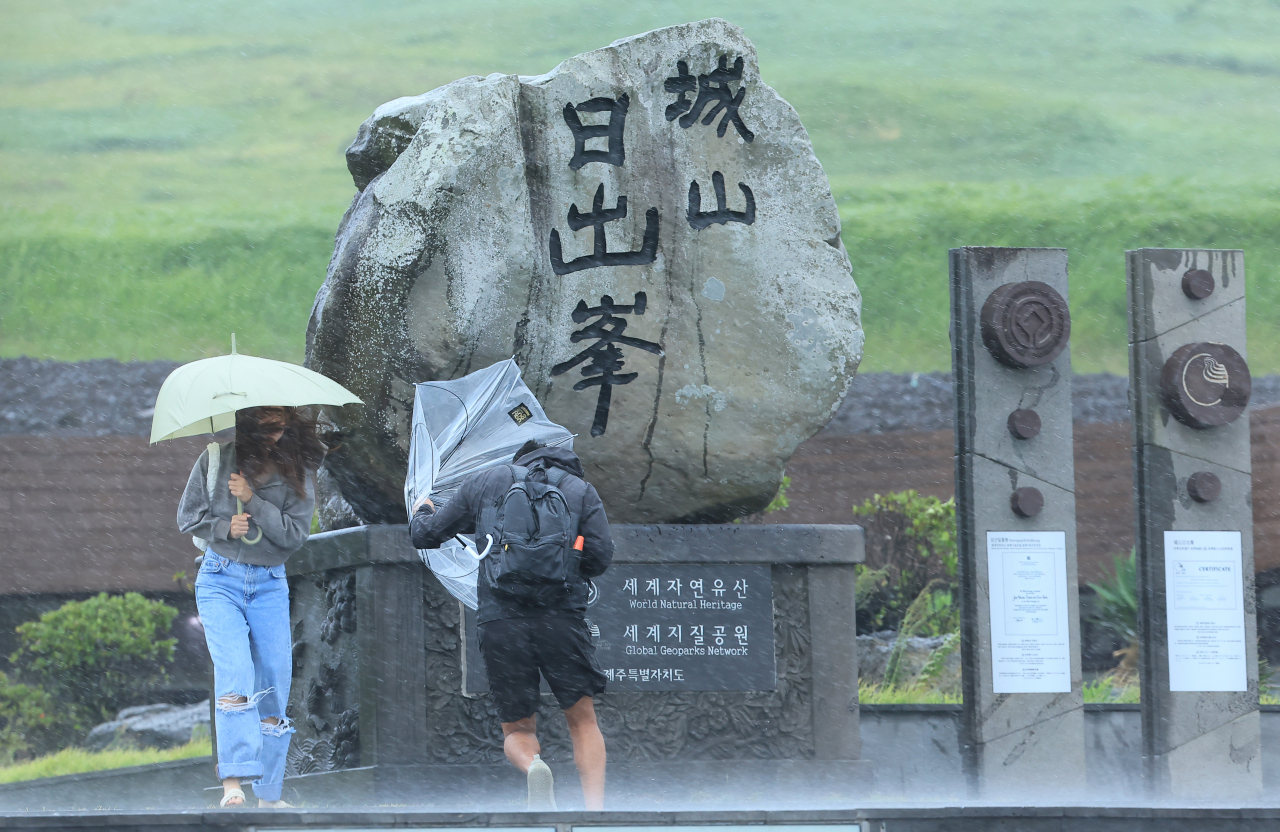 As Typhoon Khanun approaches the Korean Peninsula, tourists visiting Seongsan Ilchulbong in Seogwipo, Jeju Island, weather the strong rain and wind. Evacuations have been ordered as Khanun approaches the Korean Peninsula. (Yonhap)