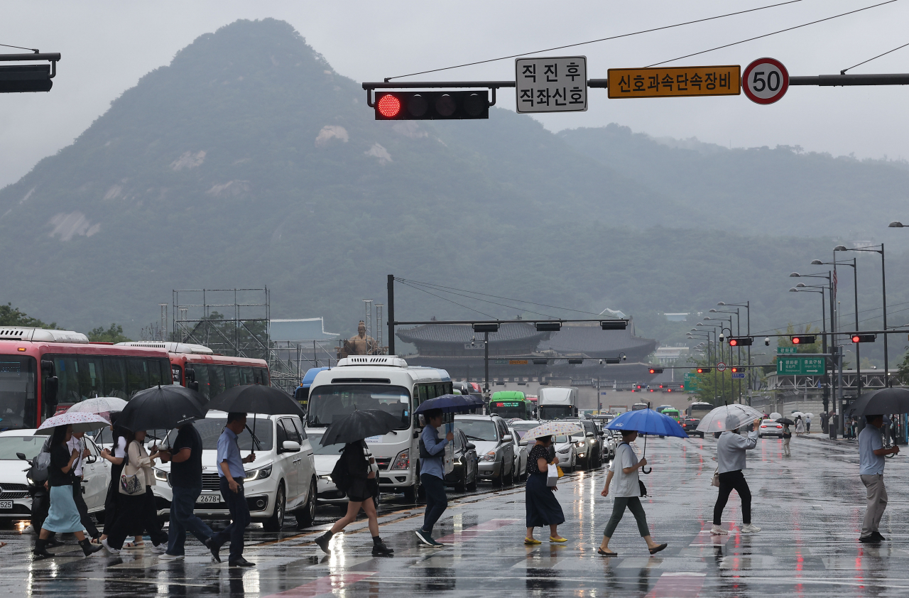 People cross the street in Gwanghwamun Plaza in central Seoul on Friday. (Yonhap)