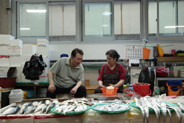 President Yoon Seok Yeol speaks with a merchant during his visit to a traditional marketplace in Geoje, South Gyeongsang Province, on Aug. 4. (The presidential office-Yonhap)