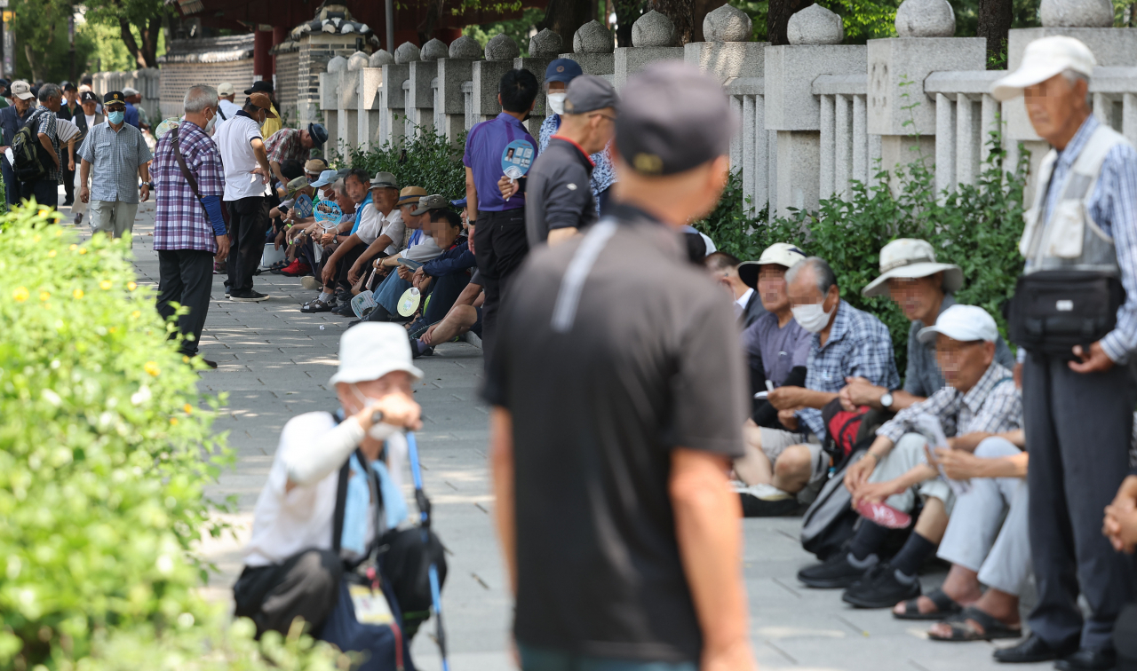 Senior citizens wait in line for free meals at Tapgol Park in central Seoul, Aug. 1. (Yonhap)