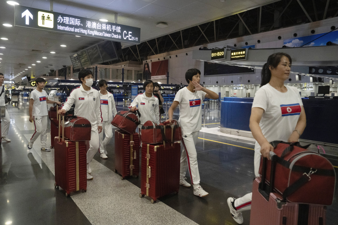 North Korean women wearing track suits with the North Korean flag and the words Taekwon-Do printed on the back walk to check in for a flight to Astana at the Capital Airport in Beijing, Friday. A team of North Korean Taekwondo athletes are reportedly travelling via China to Astana, capital of Kazakhstan, to compete in a Taekwondo competition. (AP-Yonhap)