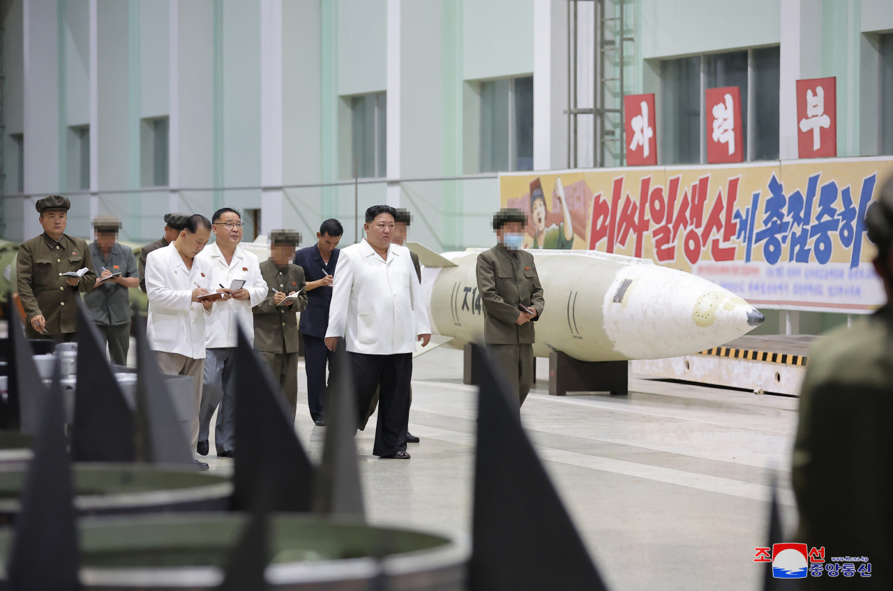 This photo, provided by North Korea's official Korean Central News Agency on Aug. 14, shows North Korean leader Kim Jong-un (second from right) on a two-day inspection of major munitions factories, including one producing tactical missiles, while calling for a "rapid" improvement of the country's missile production capabilities. (Yonhap)