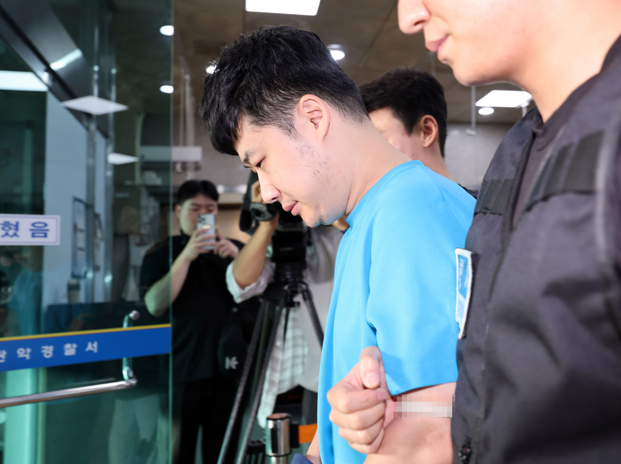 A suspect of a stabbing spree in southern Seoul in July -- a 33-year-old man Cho Seon (second from left, in sky blue T-shirt) is en route from Gwanak Police Station to the prosecutors' office on July 28. (Yonhap)