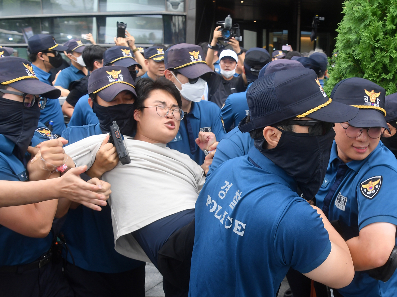 Police officers escort a protester away from the Japanese embassy in Seoul on Thursday. (Yonhap)