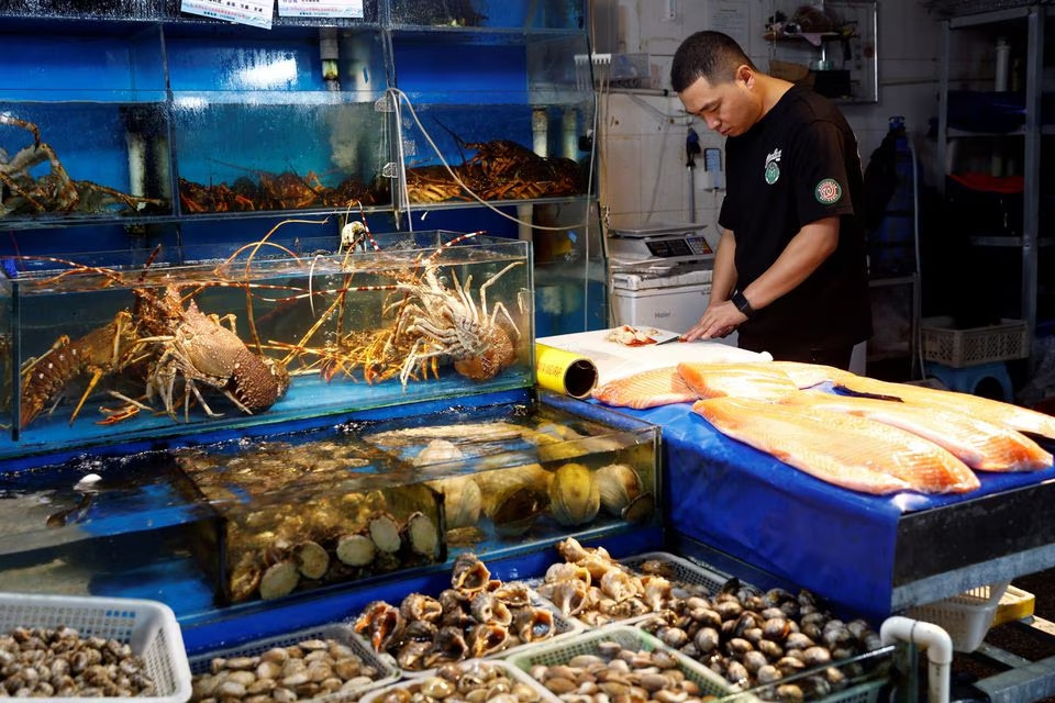 A vendor processes surf clams at a fish and seafood stall, at a seafood market in Beijing, China on Aug. 24. (Reuters)