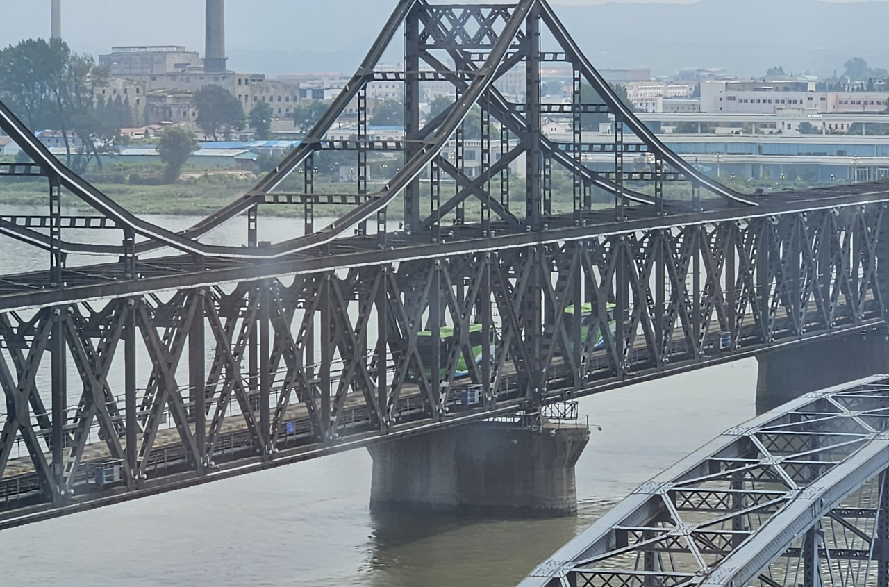 This file photo, taken Aug. 16, 2023, shows buses crossing a bridge from North Korea's border city of Sinuiju to China's Dandong. (Yonhap)