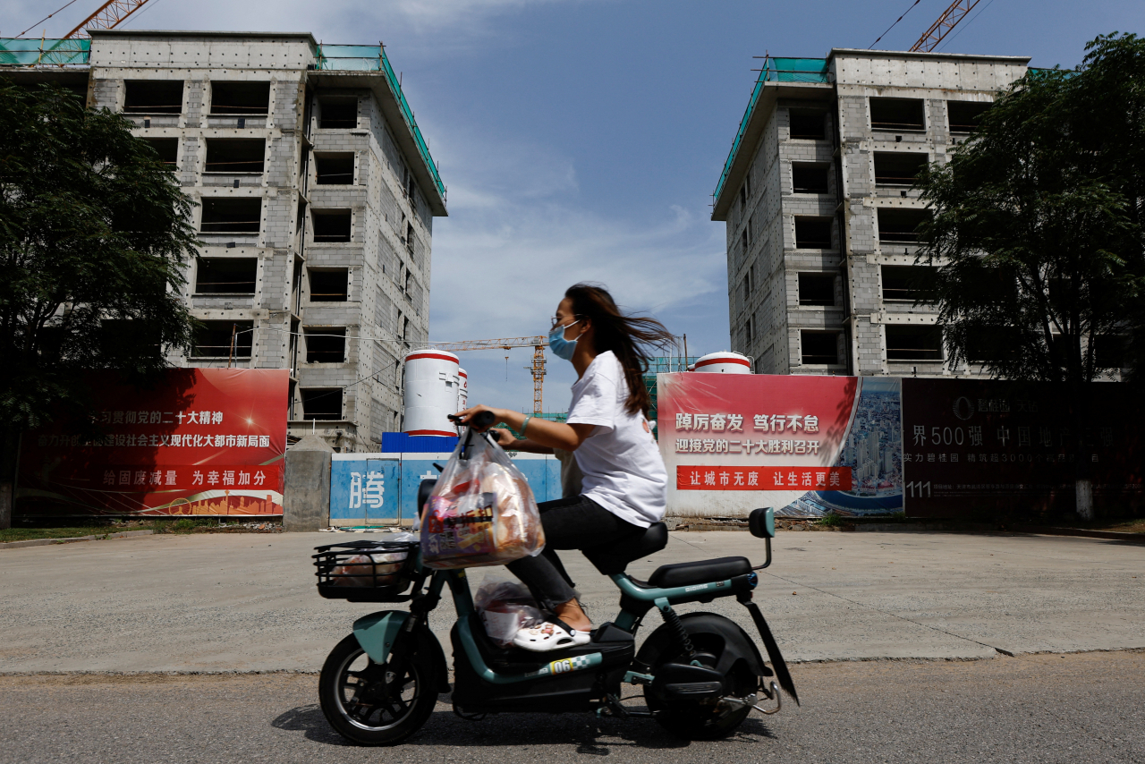 A person rides a scooter past a construction site of residential buildings by Chinese developer Country Garden, in Tianjin, China, Tuesday. (Reuters-Yonhap)