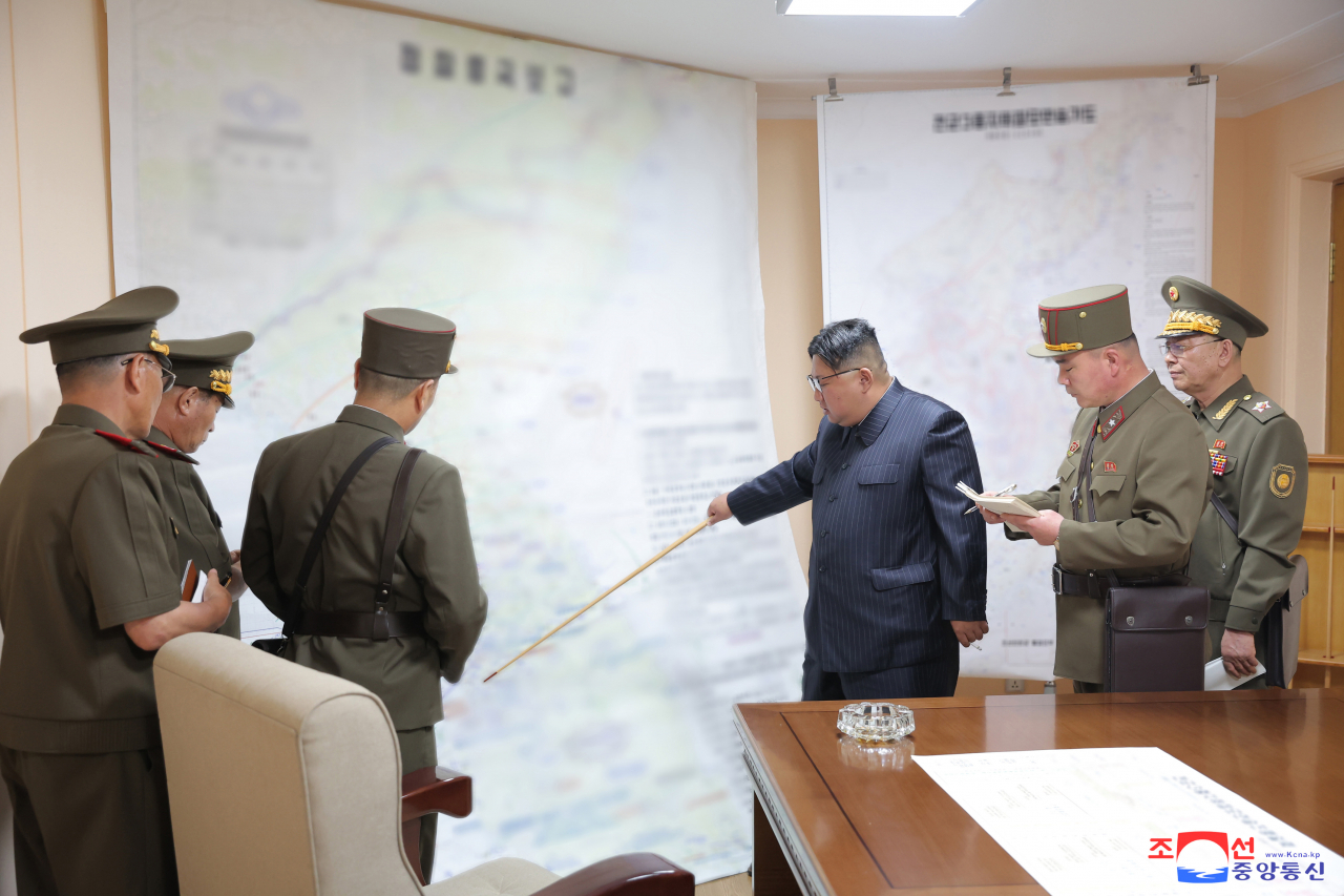 This photo, published by North Korea's Korean Central News Agency on Thursday, shows the North's leader Kim Jong-un (third from right) pointing at a South Korean region with a baton during a visit to the training command post of the General Staff of the North Korean army as the country conducted military command drills involving the entire army on Tuesday. (Yonhap)