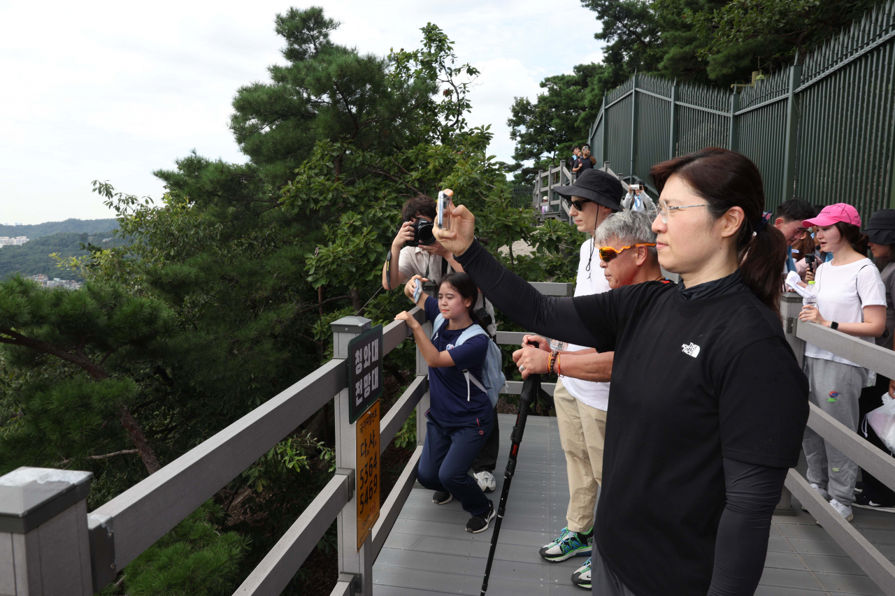 Second Vice Culture Minister Jang Mi-ran captures the view with her phone at a resting point in Bugaksan, northern Seoul, Tuesday. (Culture Ministry)