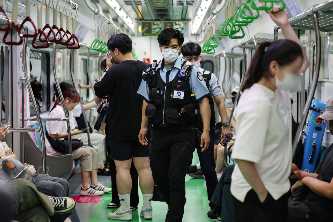 Two police officials patrol the Line No. 2 subway from Dangsan Station heading to City Hall Station on Aug. 20. (Yonhap)