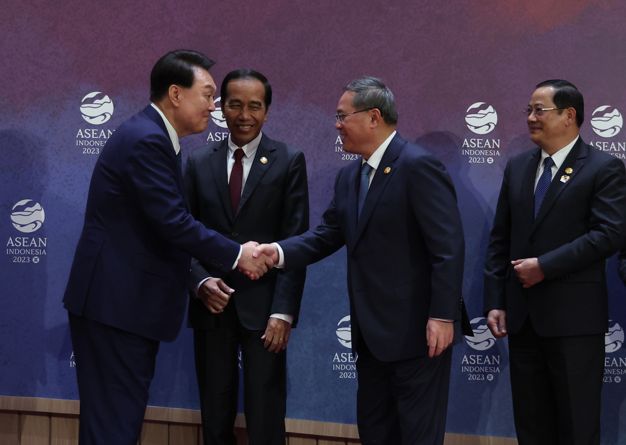 President Yoon Suk Yeol (left) shakes hands with Chinese Premier Li Qiang after taking a photo at the ASEAN+3 summit held at the Jakarta Convention Center in Indonesia on Wedneday. Indonesian President Joko Widodo is in the middle, and Laos Prime Minister Sonexay Siphandone is on the right. (Yonhap)
