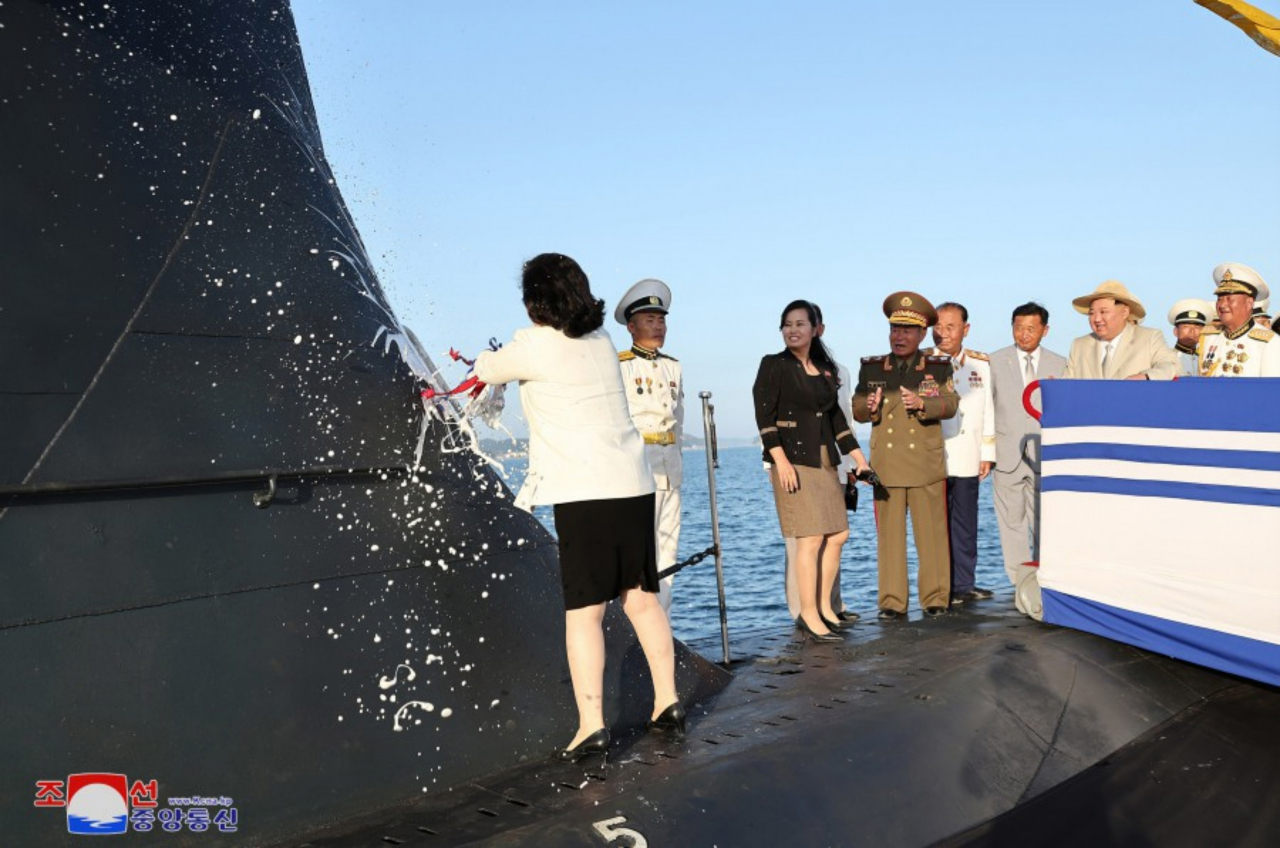 This photo, provided by North Korea's official Korean Central News Agency on Friday, shows North Korean Foreign Minister Choe Son-hui breaking a bottle of champagne against a submarine's conning tower as the role of sponsor at the launching ceremony.(Yonhap)
