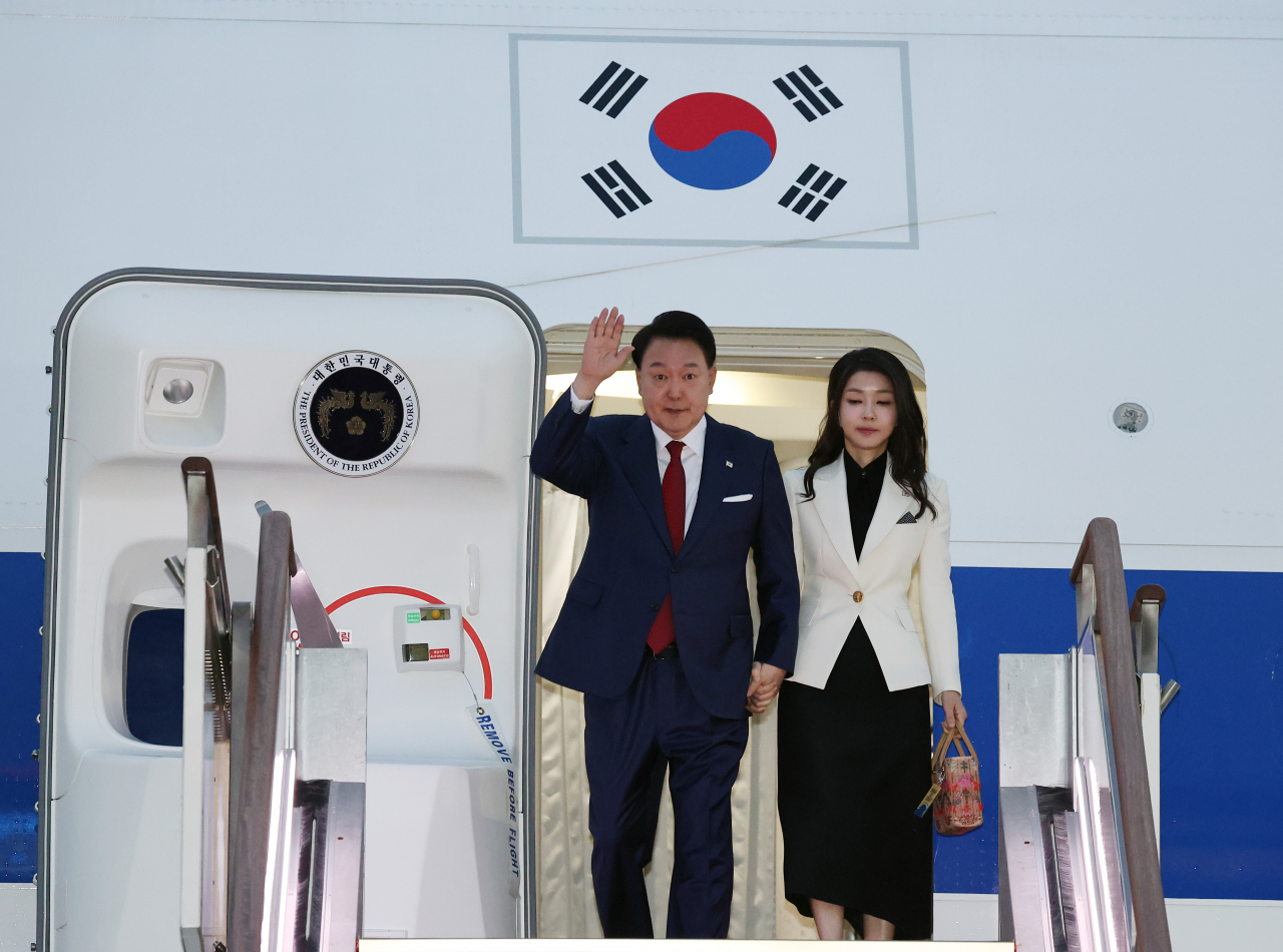 President Yoon Suk Yeol (left), alongside his wife, Kim Keon Hee, disembarks from the presidential plane at Seoul Air Base in Seongnam, south of Seoul, on Monday, after visiting Indonesia and India to attend summits involving the Association of Southeast Asian Nations and the Group of 20. (Yonhap)