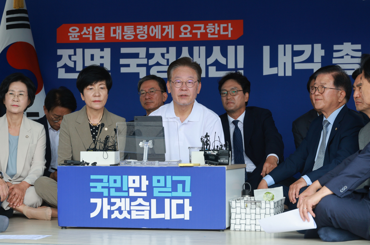 Rep. Lee Jae-myung (center), on a hunger strike protesting “tyranny of the Yoon administration,” sits inside a tent installed outside the National Assembly main building on Monday. Around him are fellow Democratic Party of Korea lawmakers. (Yonhap)