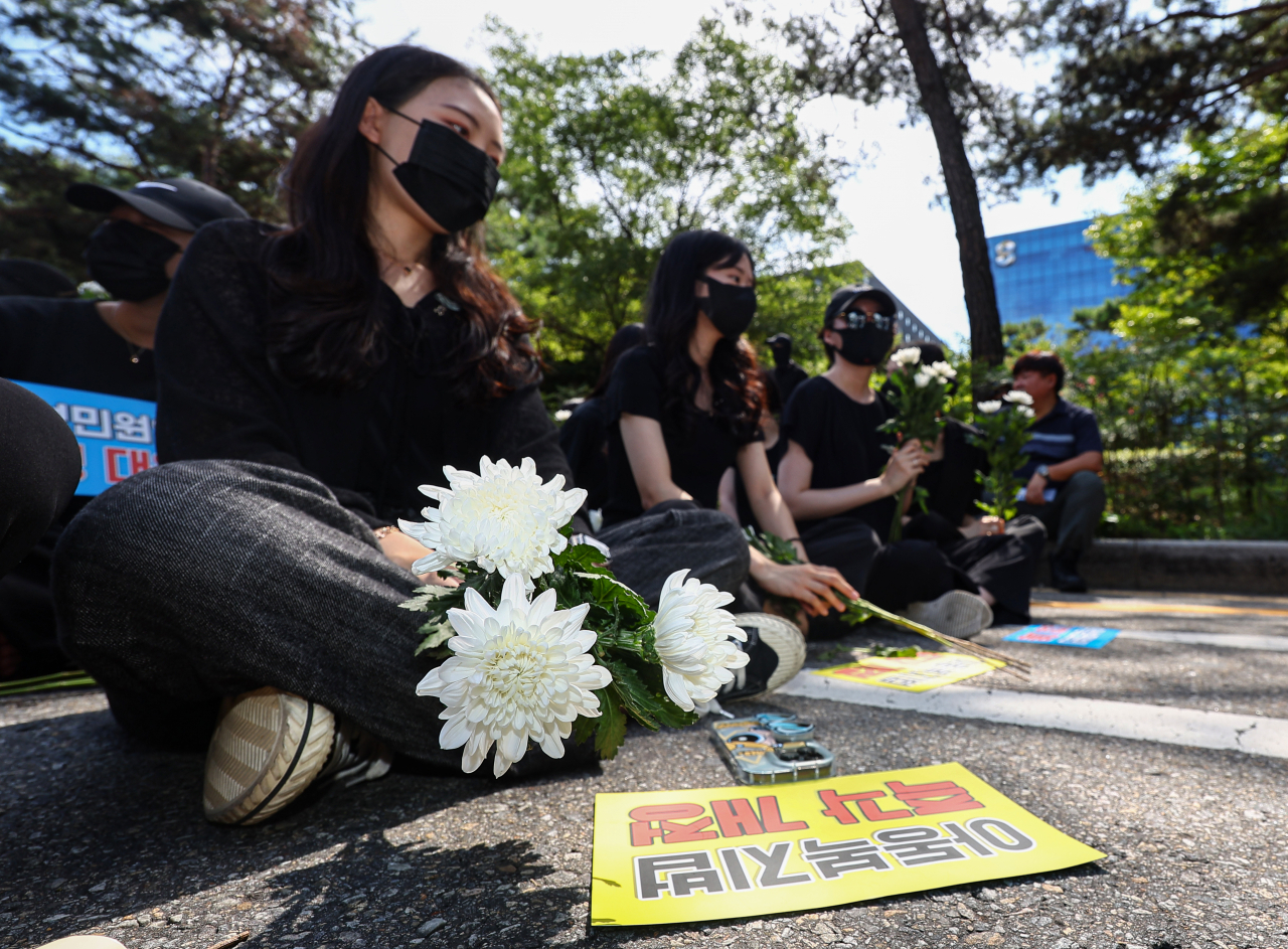 Teachers attend a rally held in front of the National Assembly in Seoul with flowers to mourn the death of fellow colleagues on Sept. 2. (Yonhap)