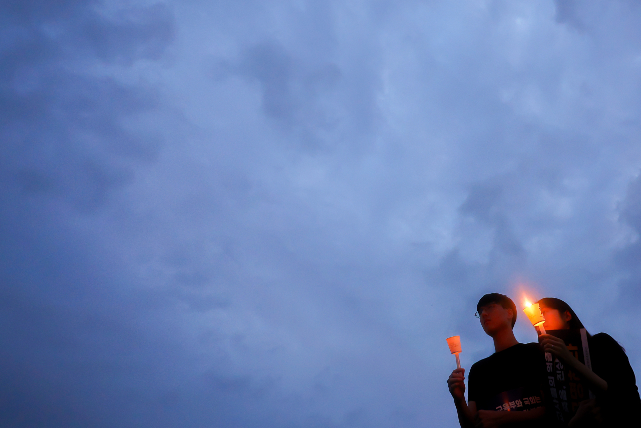 Young teachers hold candles at the candlelight vigil at Seoul National University of Education in Seoul’s Seocho-gu on Sept. 4 to mark the 49th day since the 23-year-old junior teacher at Seoi Elementary School took her own life on July 18. (Yonhap)