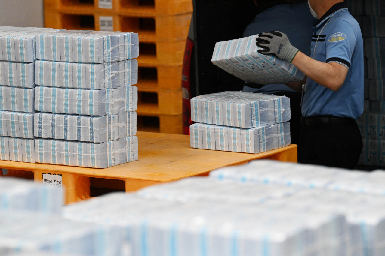 An official moves a bundle of cash at the Bank of Korea in Seoul, Tuesday. (Yonhap)