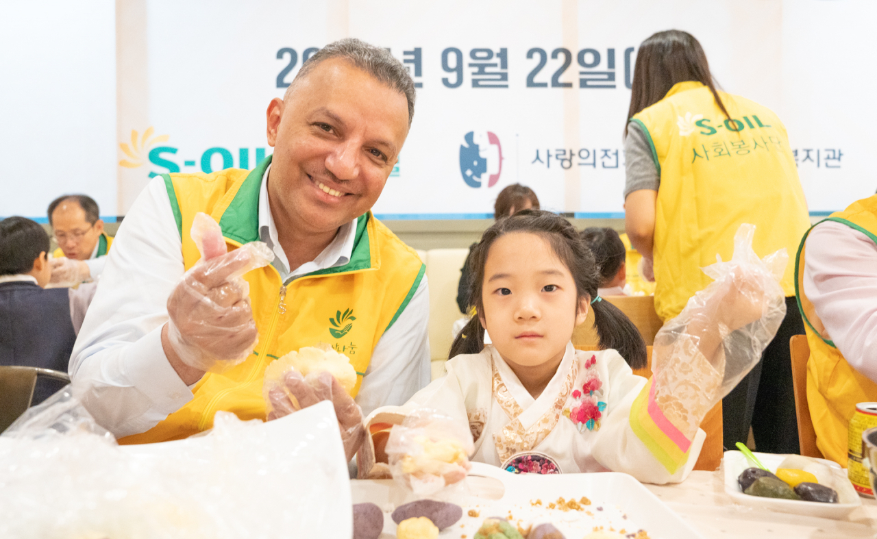 S-Oil CEO Anwar A. Al-Hejazi (left) makes songpyeon with children at a charity event held ahead of Chuseok at the company's headquarters in Mapo-gu, Seoul, on Friday. (S-Oil)