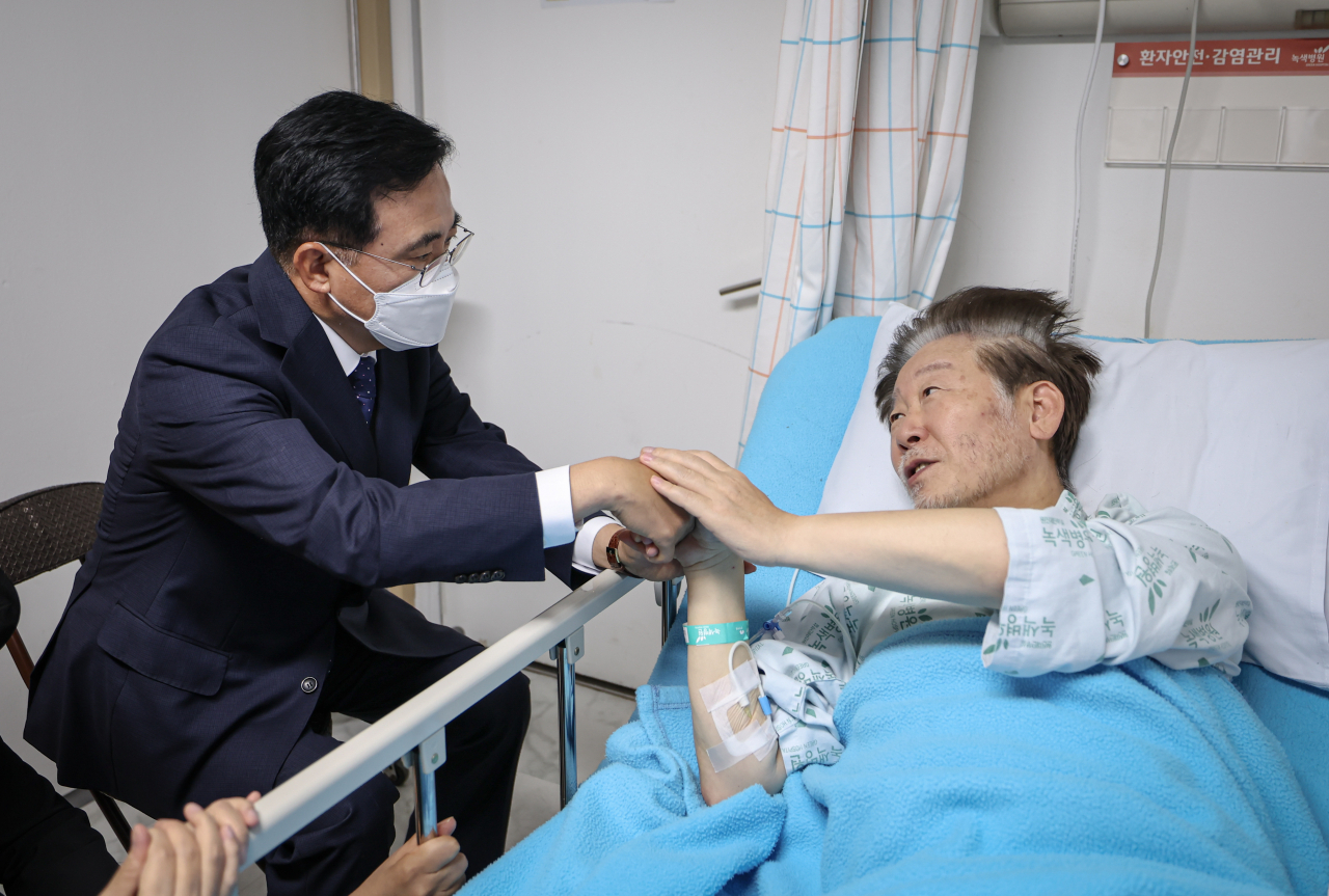 Democratic Party leader Lee Jae-myung (right) receiving treatment at a hospital on Friday. (Yonhap)