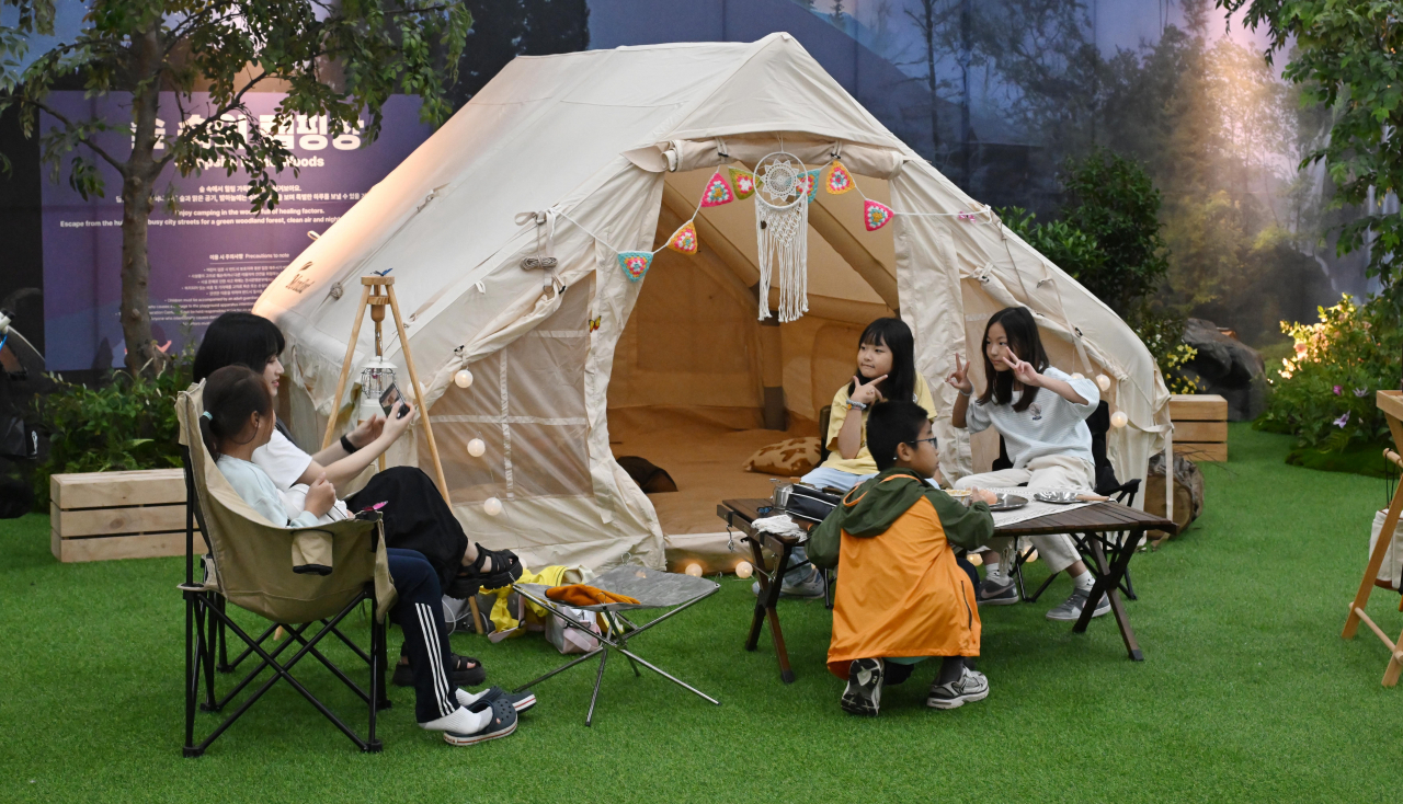 Visitors pose for photos at a camping gear exhibition in the Healing Hall at the Gangwon Forestry Exhibition 2023's main venue in Goseong, Gangwon Province on Friday. (Lee Sang-sub/ The Korea Herald)