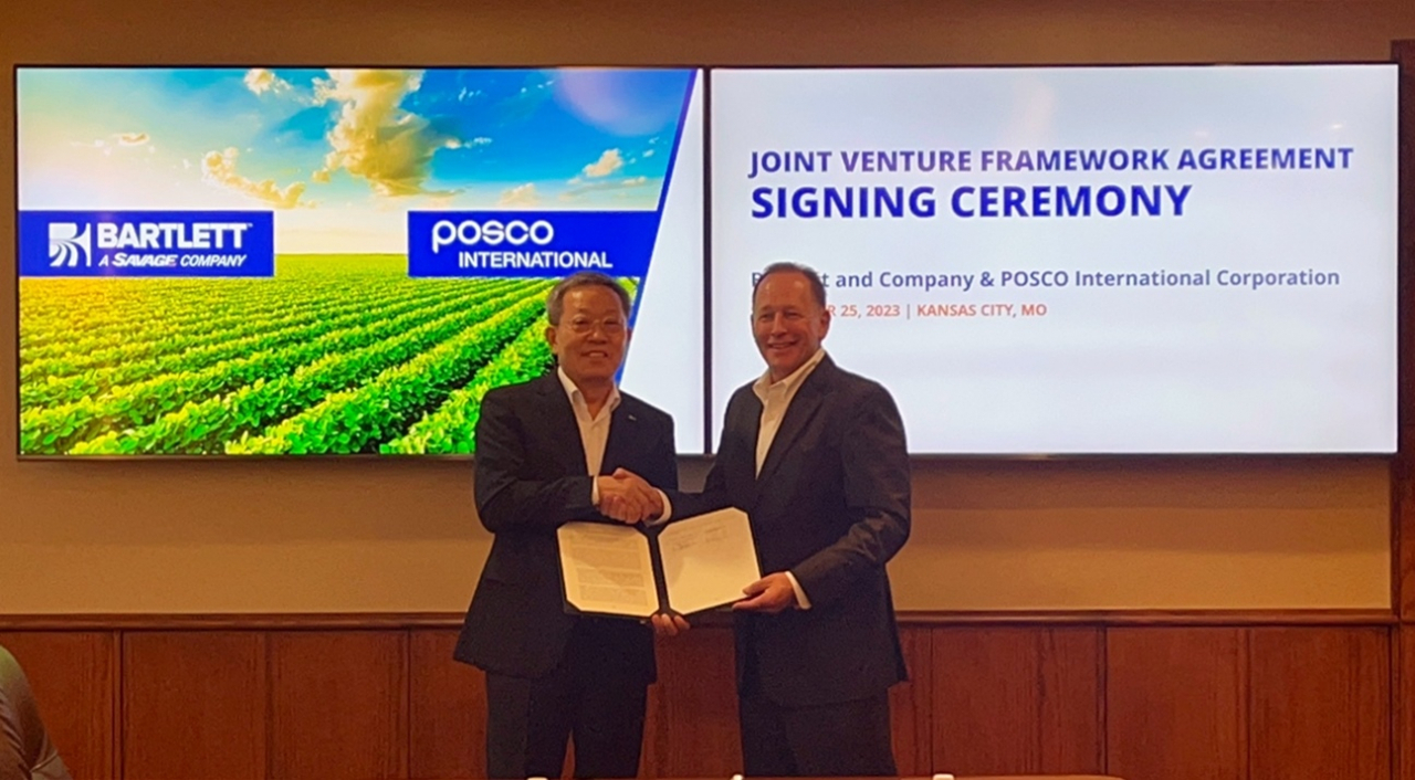 Posco International Vice Chairman and CEO Jeong Tak (left) poses for a photo with Kirk Aubry, CEO and president of Savage Companies, the parent of Bartlett and Co., during the signing ceremony for their joint venture framework agreement, in Kansas City, Missouri, on Monday. (Posco International)