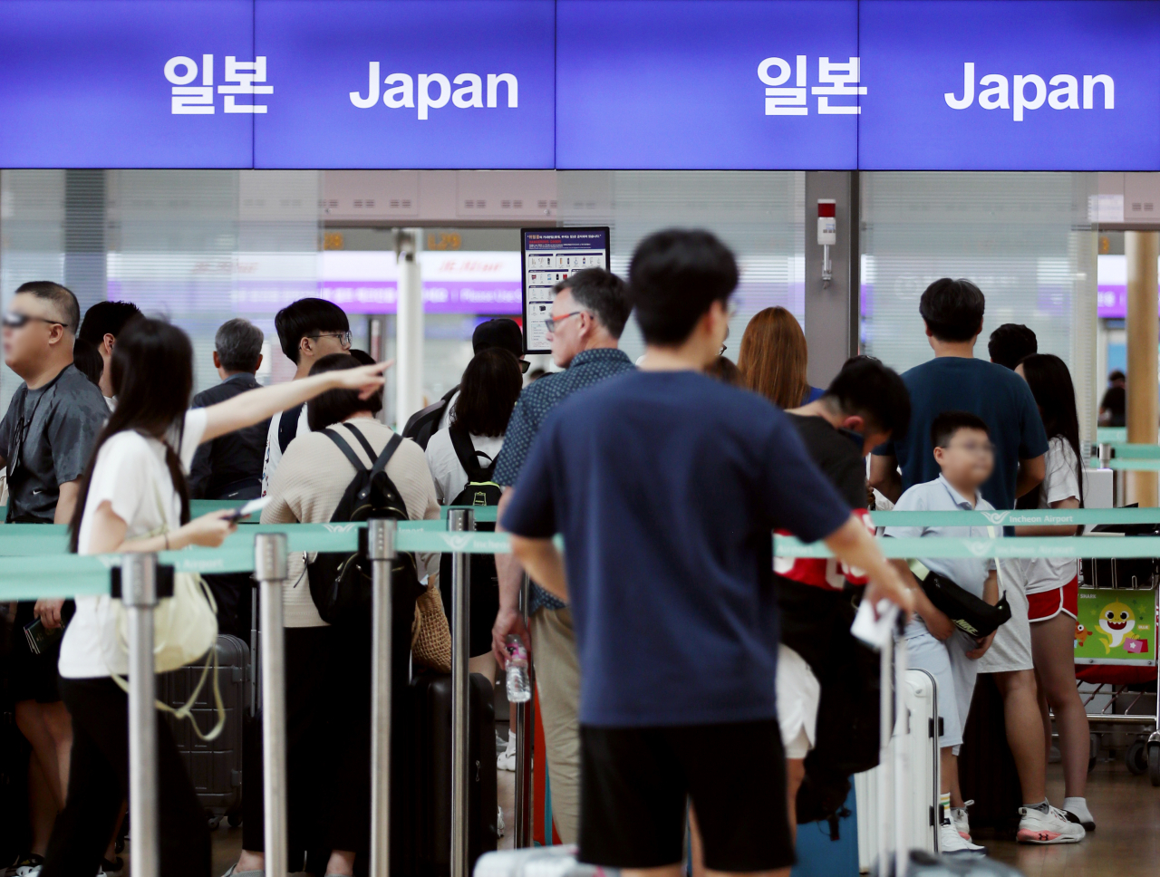 Travelers wait in line at check-in counters in Incheon Airport, July 20. (Newsis)