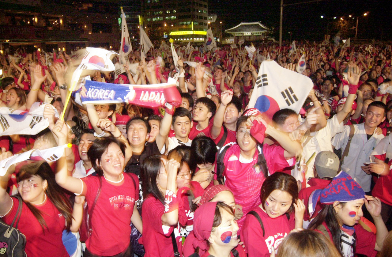 South Korean soccer fans, clad in red T-shirts, cheer for the national team during the 2002 World Cup tournament in this filed photo dated July 6, 2002. (Korea Herald DB)