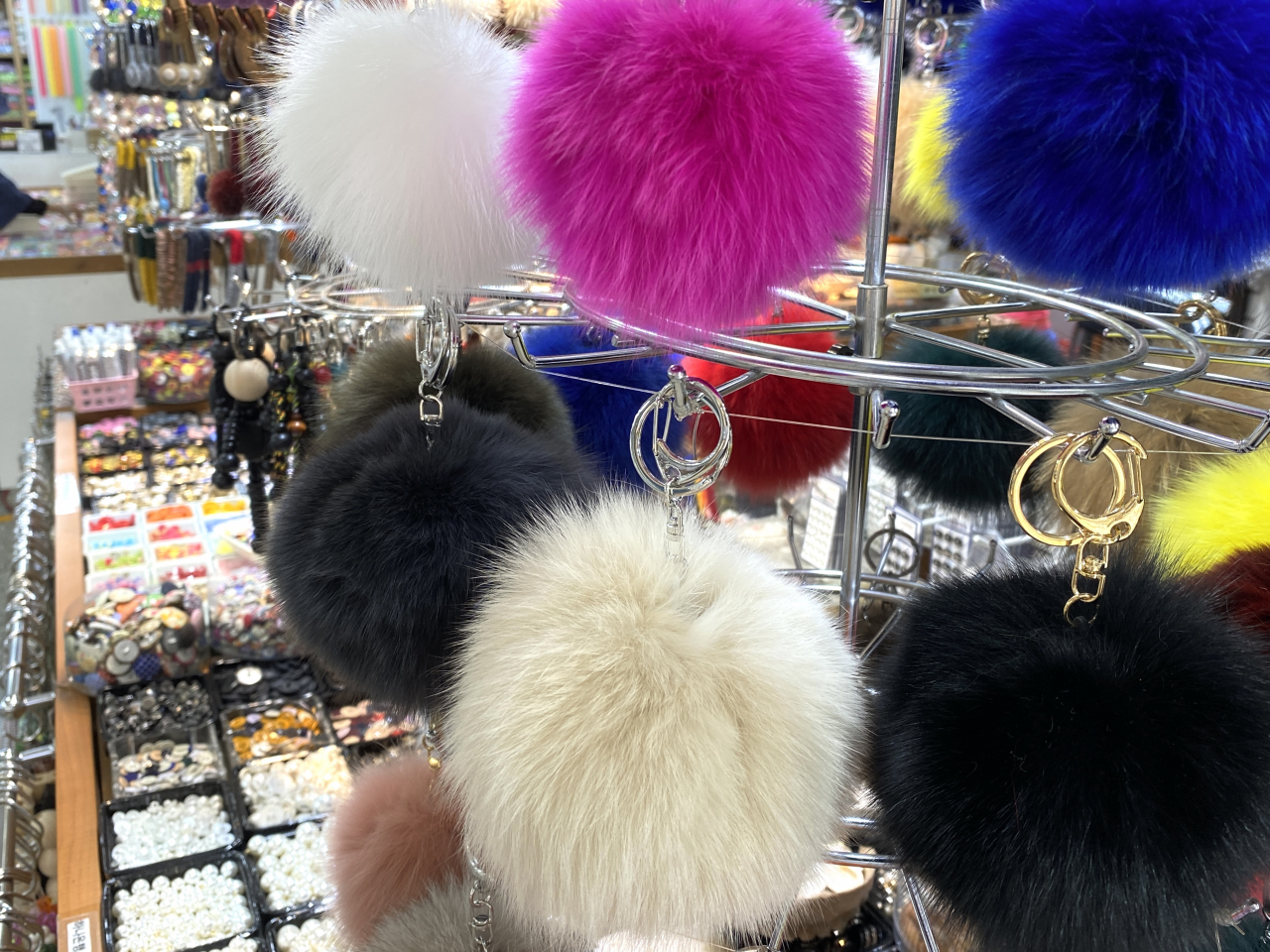 Fluffy ball keychains are hung on a display stand. (Hwang Joo-young/The Korea Herald)