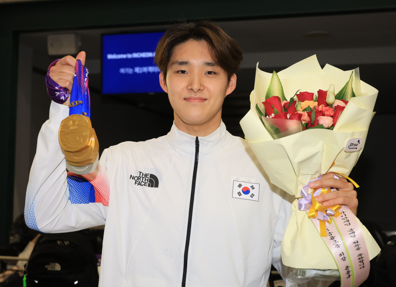 South Korean swimmer Kim Woo-min poses with his three gold medals won at the 19th Asian Games in Hangzhou, China, after arriving at Incheon International Airport, Sept. 30. (Yonhap)