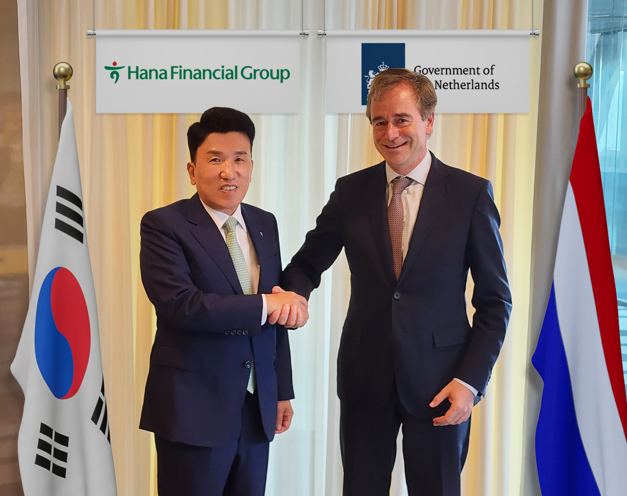 Hana Financial Group Chairman Ham Young-joo (left) shakes hands with Rene van Hell, ambassador for sustainable development for the Netherlands, in The Hague, Netherlands, Friday. (Hana Financial Group)