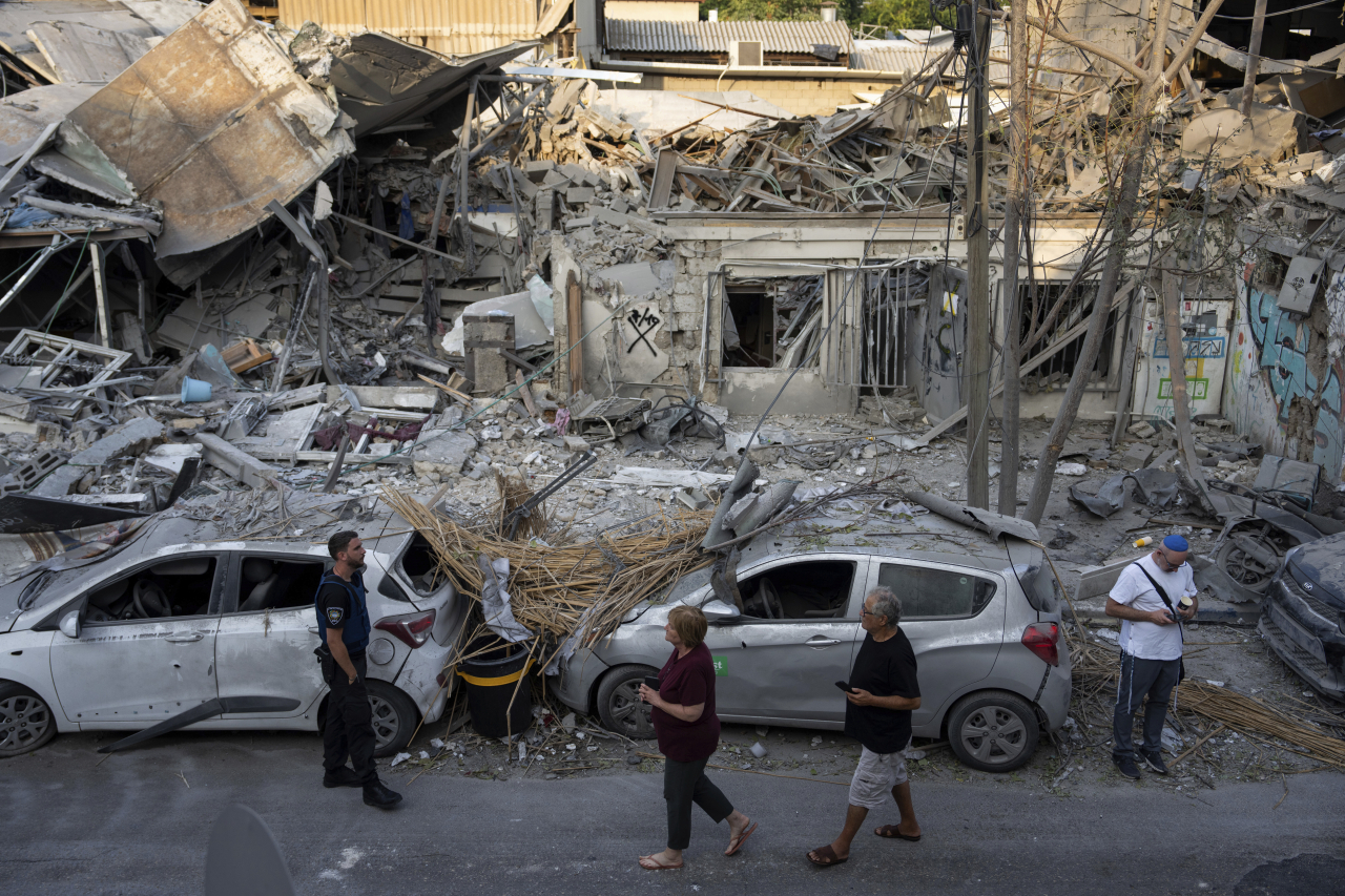 Israelis inspect the rubble of a building a day after it was hit by a rocket fired from the Gaza Strip, in Tel Aviv, Israel, October 8, 2023. (AP-Yonhap)