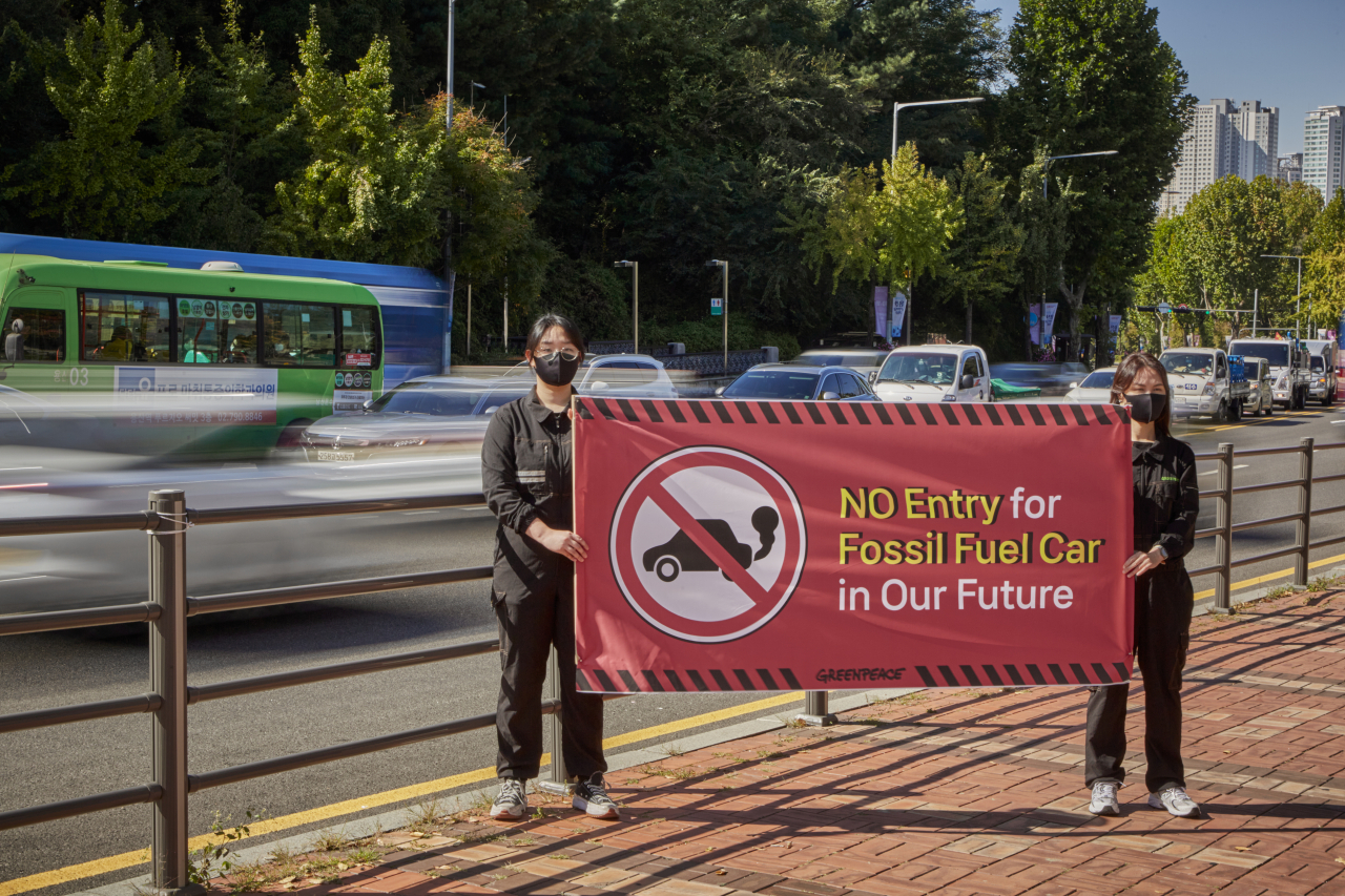 Greenpeace campaigners hold up a banner calling for zero emissions efforts from automakers on a sidewalk in Seoul. (Greenpeace)