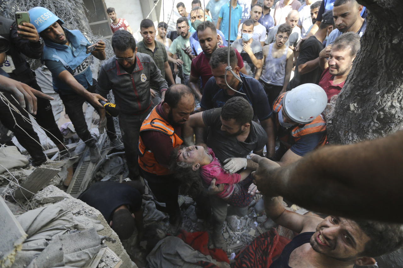 Palestinians rescue a child from under the rubble after Israeli airstrikes in Gaza City, Gaza Strip, Wednesday. (AP-Yonhap)