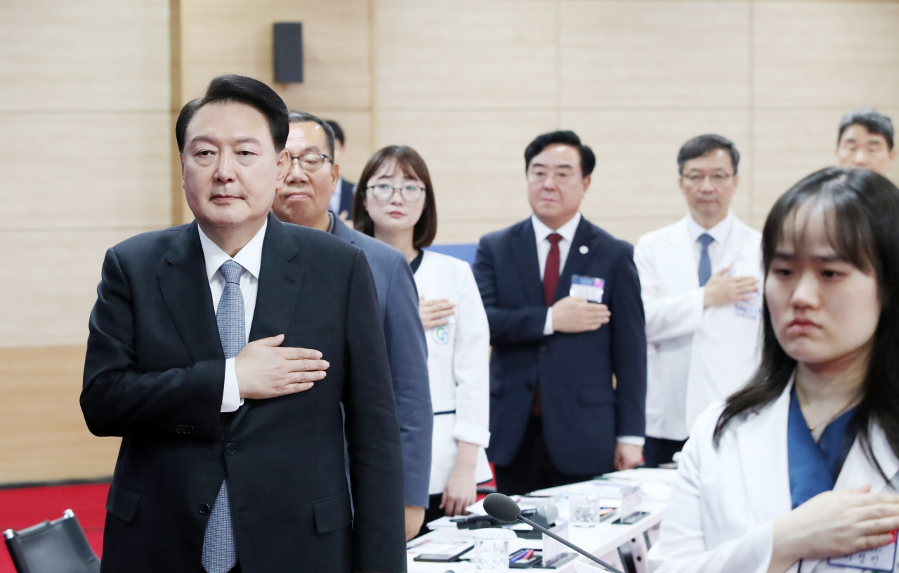 President Yoon Suk Yeol (left) salutes to the national flag of South Korea along with participants in the meeting held Thursday at Chungbuk National University. (Yonhap)