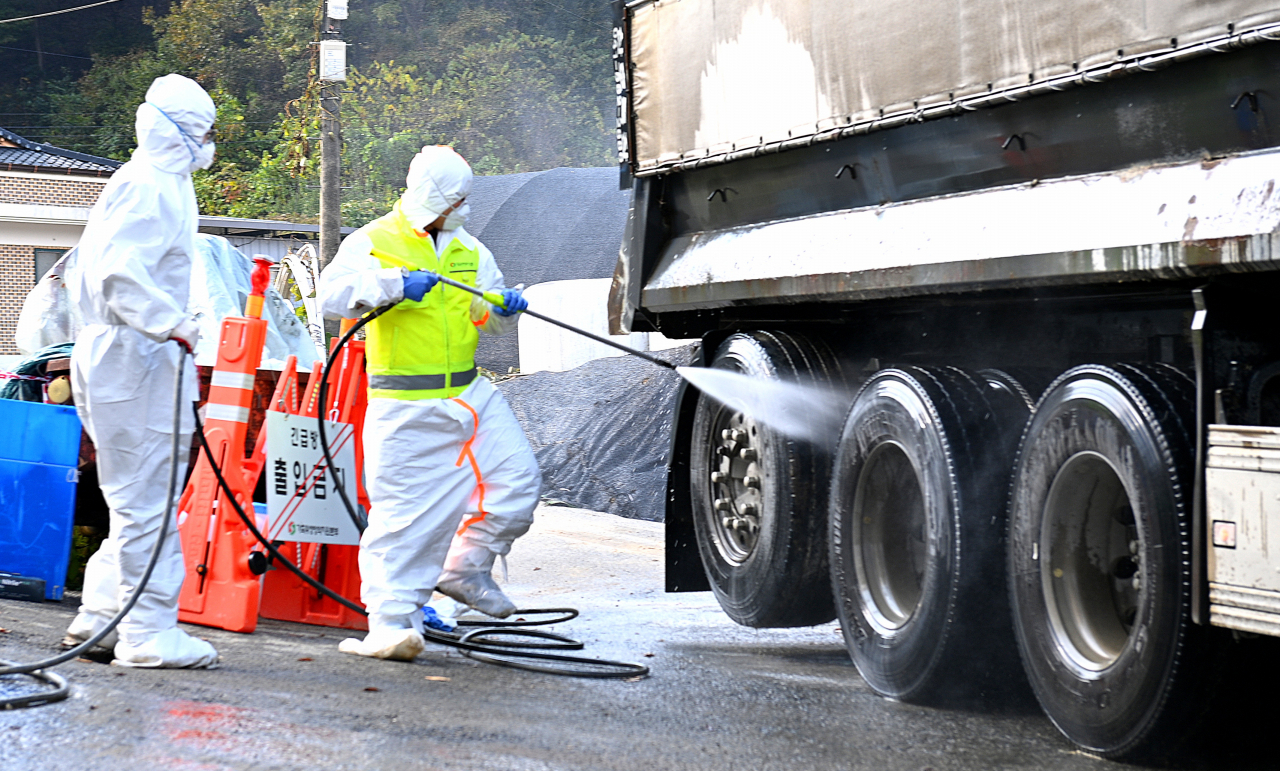 Workers disinfect a truck at a farm in Eumseong, North Chungcheong Province, Monday. (Eumseong County)